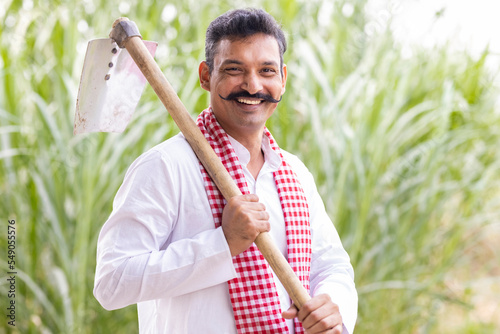 Photography Portrait of happy Indian farmer holding hoe.