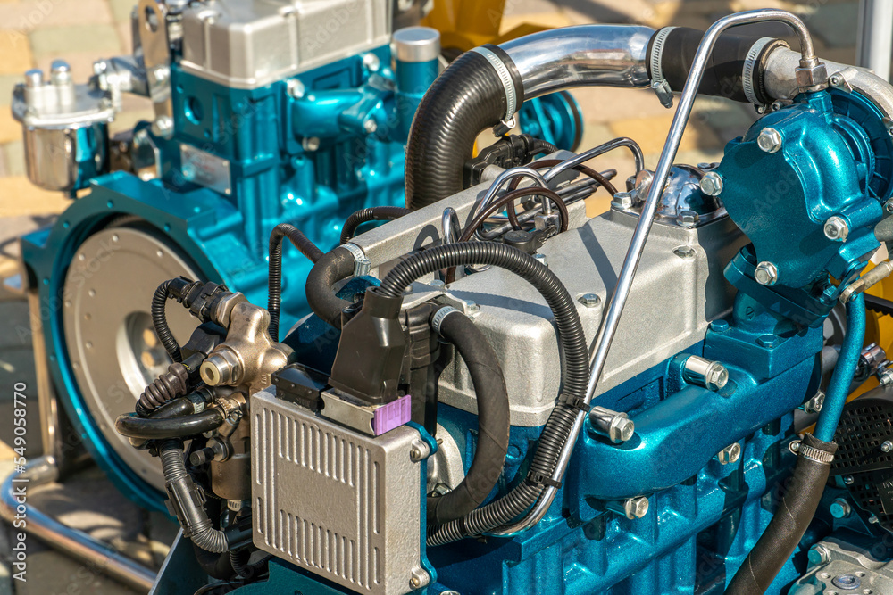 Obraz premium A new modern car engine on the street. The concept of a modern powerful automobile engine for heavy industrial machinery. Mechanical parts of the motor close-up.
