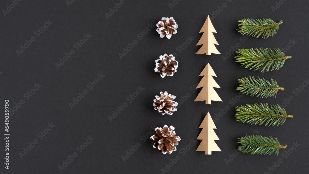 Christmas banner with spruce twigs, paper trees and pine cones on a dark background Christmas banner with spruce twigs, paper trees and pine cones on a dark background