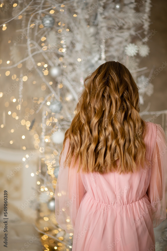 Vinnytsia, Ukraine. December 25, 2022: A girl decorates a Christmas tree at home with white toys for the New Year. 2023 is coming Vinnytsia, Ukraine. December 25, 2022: A girl decorates a Christmas tree at home with white toys for the New Year. 2023 is coming