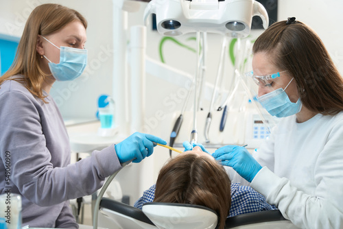 Woman doctor performs a dental procedure on a young patient