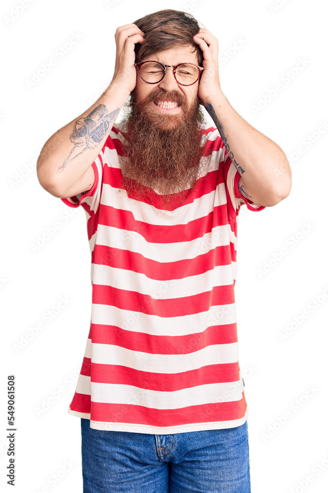 Handsome young red head man with long beard wearing casual clothes suffering from headache desperate and stressed because pain and migraine. hands on head. Handsome young red head man with long beard wearing casual clothes suffering from headache desperate and stressed because pain and migraine. hands on head.