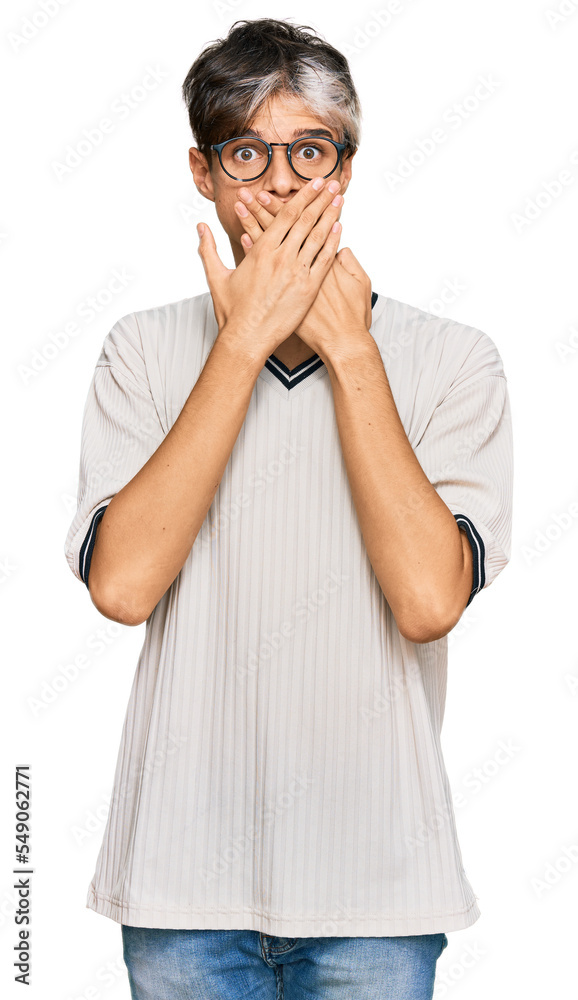 Young hispanic man wearing casual clothes and glasses shocked covering mouth with hands for mistake. secret concept. Young hispanic man wearing casual clothes and glasses shocked covering mouth with hands for mistake. secret concept.