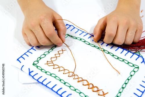 The closeup of hands sewing a colorful card during school activities. An ideal DIY stitch with needle and thread exercise for children.
Art class idea for a creative project.
