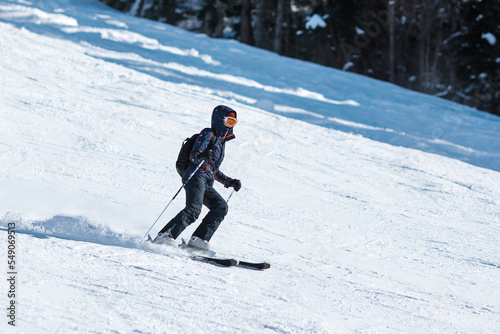 Amateur female skier sliding down the slope at a mountain resort.