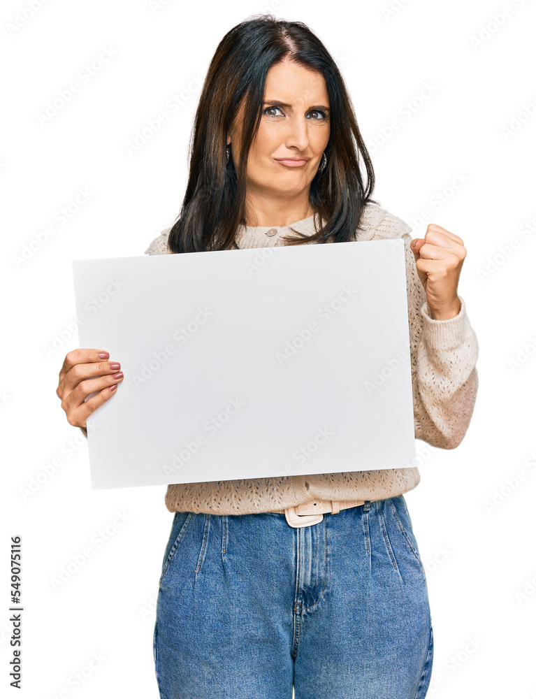 Middle age brunette woman holding blank empty banner screaming proud, celebrating victory and success very excited with raised arms Middle age brunette woman holding blank empty banner screaming proud, celebrating victory and success very excited with raised arms