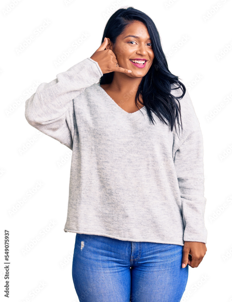 Hispanic woman with long hair wearing casual clothes smiling doing phone gesture with hand and fingers like talking on the telephone. communicating concepts. Hispanic woman with long hair wearing casual clothes smiling doing phone gesture with hand and fingers like talking on the telephone. communicating concepts.