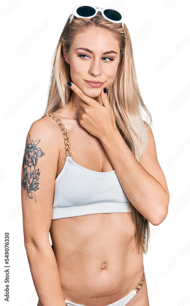 Obraz premium Beautiful young blonde woman wearing bikini with hand on chin thinking about question, pensive expression. smiling with thoughtful face. doubt concept.