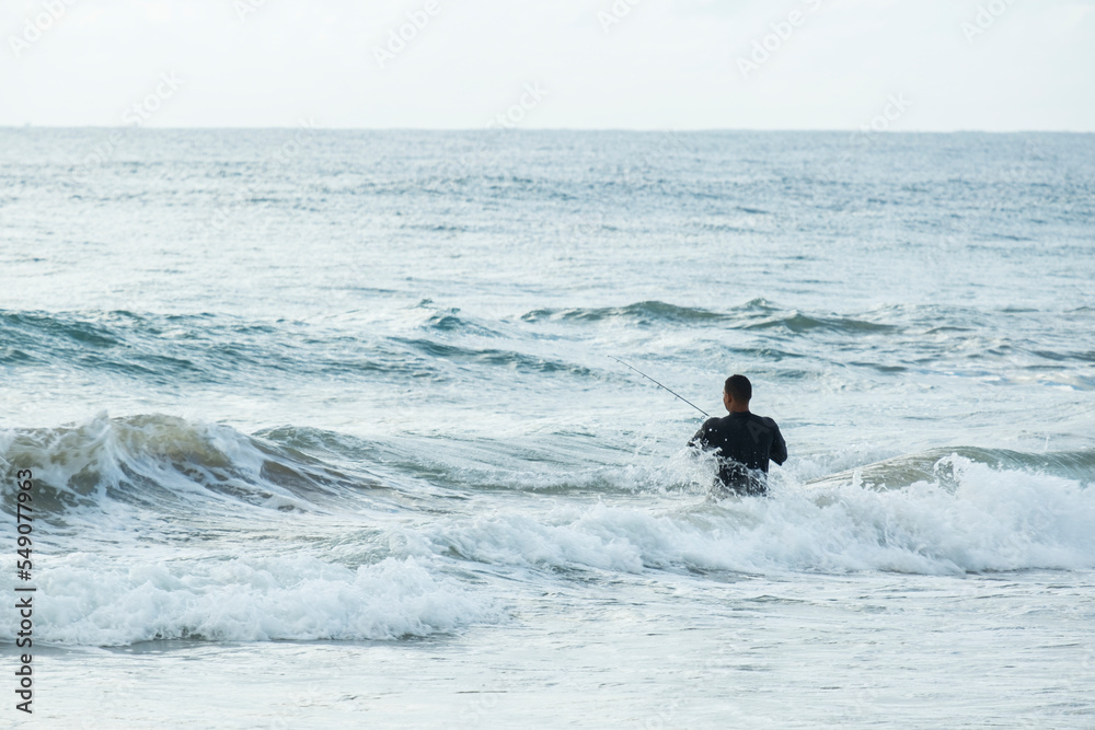 Naklejka premium man with fishing rod on the beach