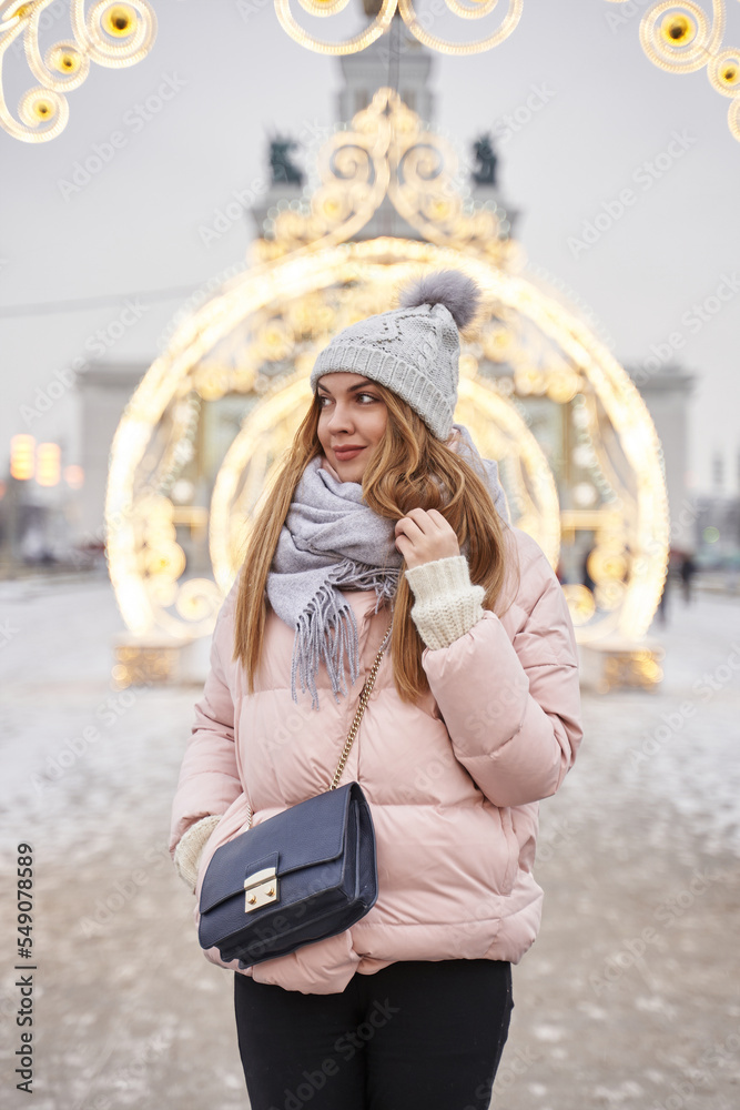 beautiful young woman in winter on the background of illuminated decorations for christmas in the city. festive illumination