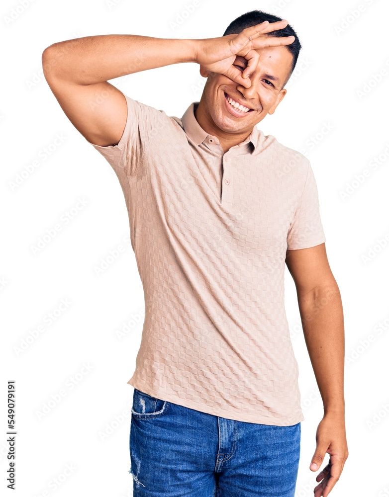 Young handsome latin man wearing casual clothes smiling happy doing ok sign with hand on eye looking through fingers Young handsome latin man wearing casual clothes smiling happy doing ok sign with hand on eye looking through fingers