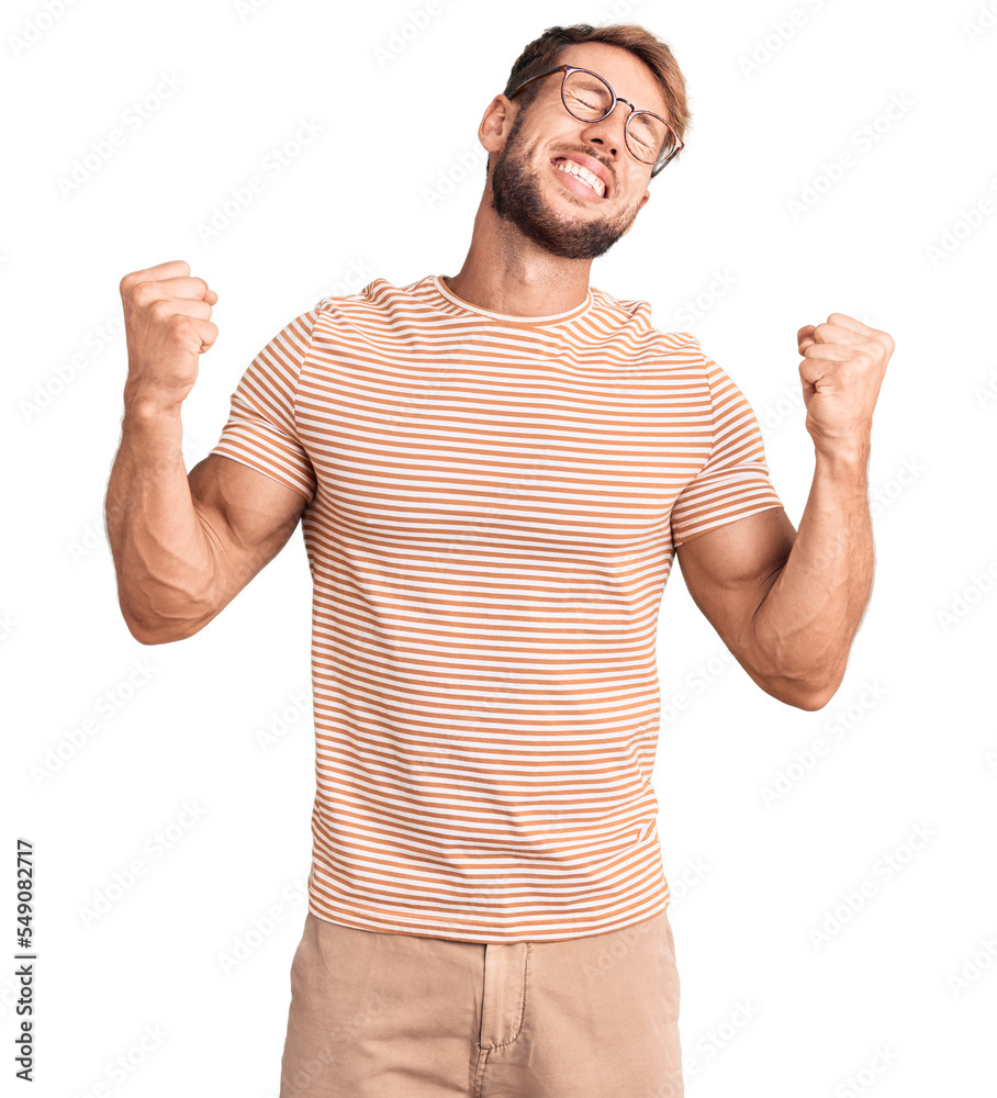 Young caucasian man wearing casual clothes and glasses very happy and excited doing winner gesture with arms raised, smiling and screaming for success. celebration concept. Young caucasian man wearing casual clothes and glasses very happy and excited doing winner gesture with arms raised, smiling and screaming for success. celebration concept.