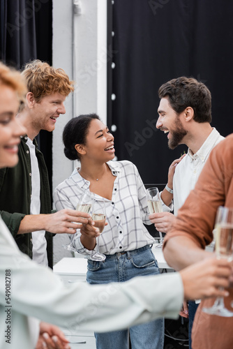 Photography Smiling multiethnic business people talking and holding champagne during corpora