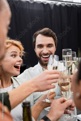 Cheerful multiethnic business people clinking champagne in office