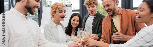 Canvas Print joyful interracial managers toasting with champagne at corporate party in office