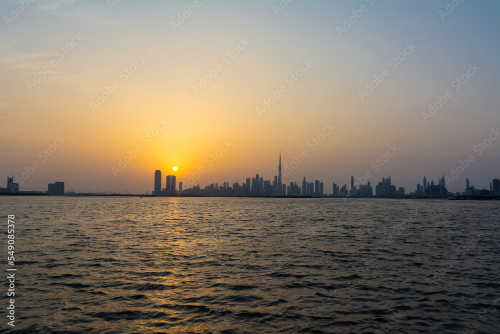 Sunset over Dubai skyscrapers with calm water and beautiful colors