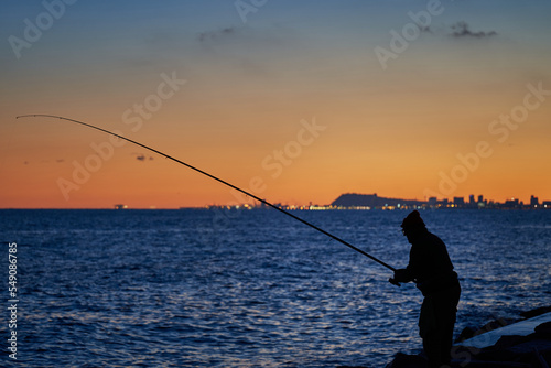 Pescador en contraluz, atardecer en el mar con la ciudad de Barcelona de fondo © Hector Milla