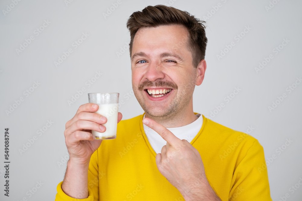 Smiling funny handsome guy 2 posing holding in hand glass of milk Smiling funny handsome guy 2 posing holding in hand glass of milk
