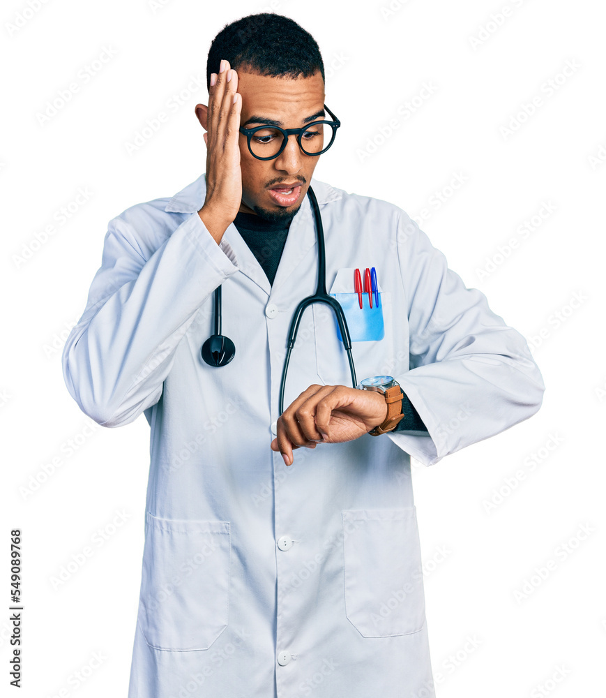 Young african american man wearing doctor uniform and stethoscope looking at the watch time worried, afraid of getting late Young african american man wearing doctor uniform and stethoscope looking at the watch time worried, afraid of getting late