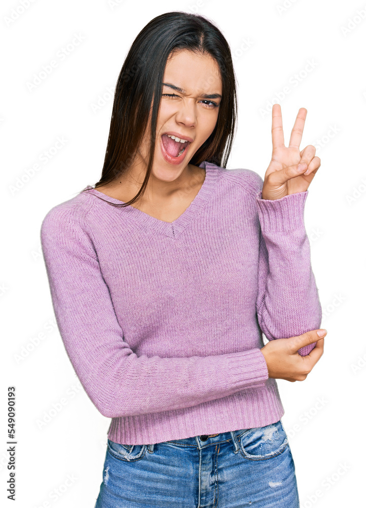 Young hispanic girl wearing casual clothes smiling with happy face winking at the camera doing victory sign. number two. Young hispanic girl wearing casual clothes smiling with happy face winking at the camera doing victory sign. number two.