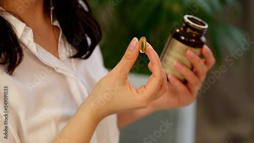 woman pours a handful of Omega 3 vitamin capsules on her hand
