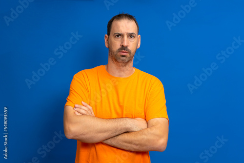 Serious latin man with beard posing with arms crossed isolated on blue studio background.