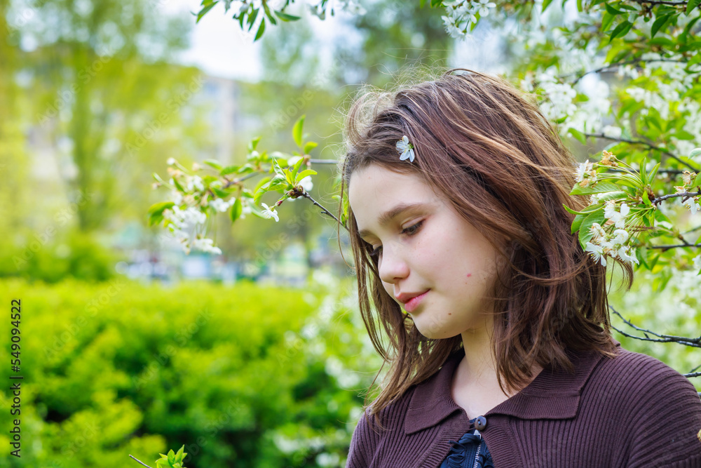 Beautiful girl among cherry flowers in spring. Portrait of a girl with brown hair and green eyes. Beautiful girl among cherry flowers in spring. Portrait of a girl with brown hair and green eyes.