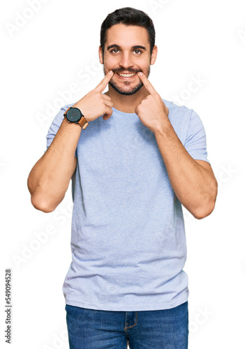 Young hispanic man wearing casual clothes smiling with open mouth, fingers pointing and forcing cheerful smile