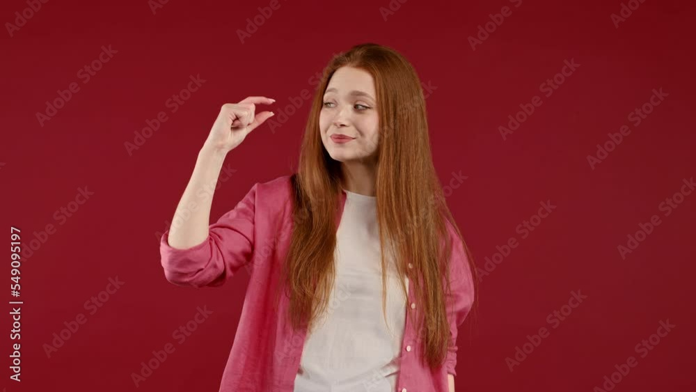 Big large and small tiny concept. Woman showing difference between invisible abstract subject or object sizes. Size matters. Red studio background Big large and small tiny concept. Woman showing difference between invisible abstract subject or object sizes. Size matters. Red studio background
