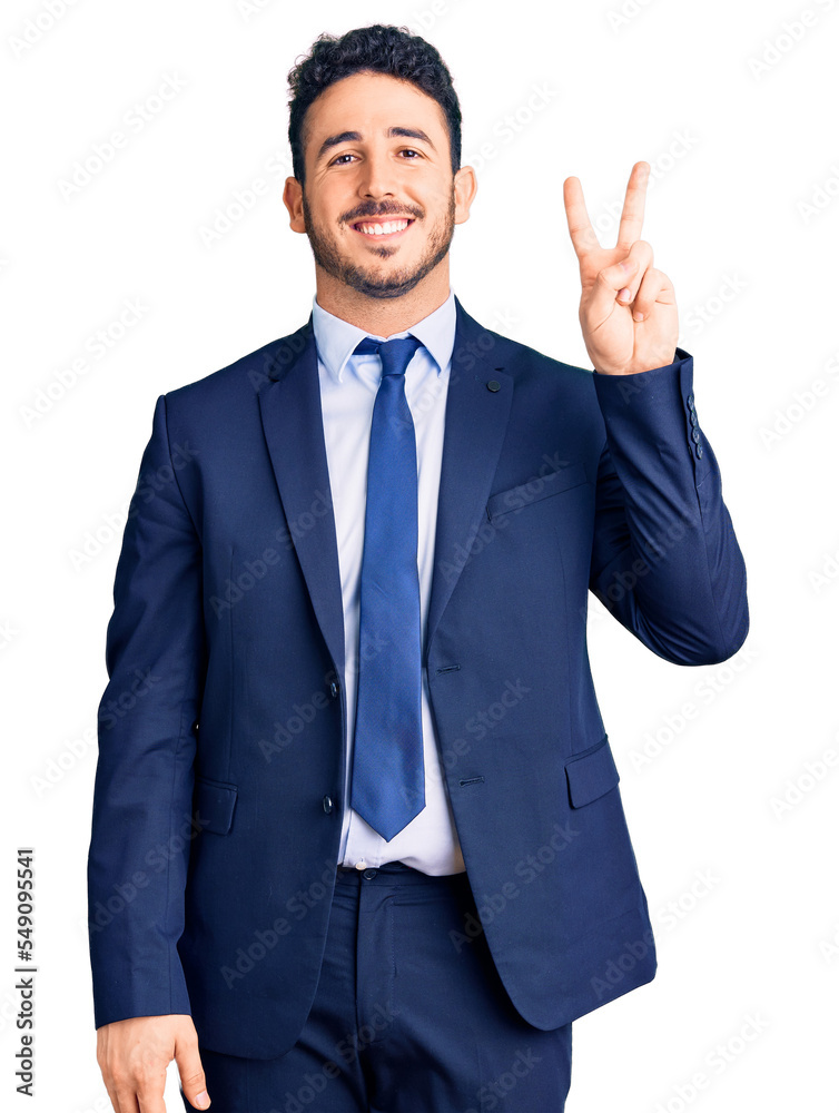 Young hispanic man wearing business clothes smiling with happy face winking at the camera doing victory sign. number two. Young hispanic man wearing business clothes smiling with happy face winking at the camera doing victory sign. number two.