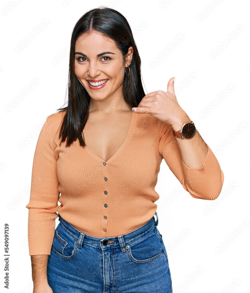 Young hispanic woman wearing casual clothes smiling doing phone gesture with hand and fingers like talking on the telephone. communicating concepts. Young hispanic woman wearing casual clothes smiling doing phone gesture with hand and fingers like talking on the telephone. communicating concepts.