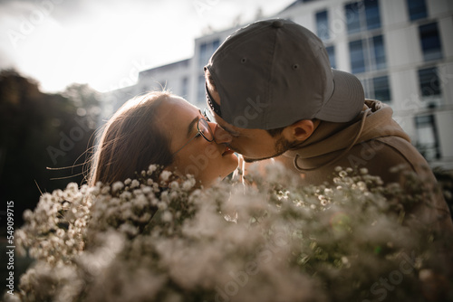 wonderful portrait of kissing young woman and man. Blurred floral bouquet in the foreground photo