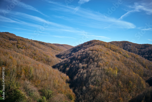 Landscape of tuscan mountains in autumn with blue sky and contrails