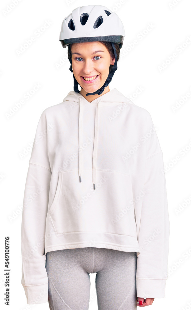 Beautiful brunette young woman wearing bike helmet and sporty clothes with a happy and cool smile on face. lucky person. Beautiful brunette young woman wearing bike helmet and sporty clothes with a happy and cool smile on face. lucky person.