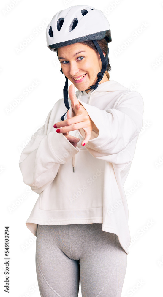 Beautiful brunette young woman wearing bike helmet and sporty clothes pointing fingers to camera with happy and funny face. good energy and vibes. Beautiful brunette young woman wearing bike helmet and sporty clothes pointing fingers to camera with happy and funny face. good energy and vibes.