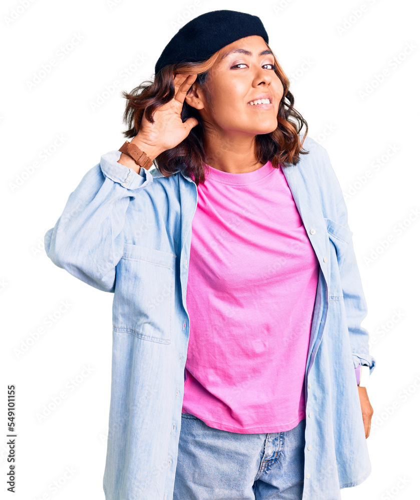 Young beautiful mixed race woman wearing french look with beret smiling with hand over ear listening an hearing to rumor or gossip. deafness concept. Young beautiful mixed race woman wearing french look with beret smiling with hand over ear listening an hearing to rumor or gossip. deafness concept.