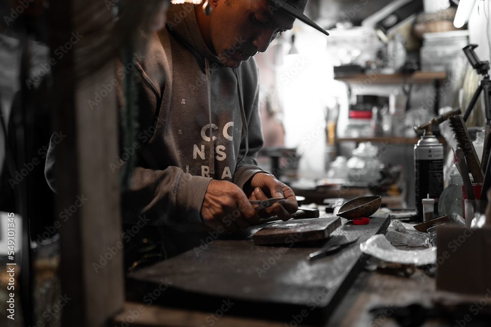 A craftsman jeweler is cutting a metal piece to create a jewel A craftsman jeweler is cutting a metal piece to create a jewel