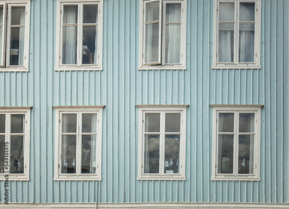Blaue Holzfassade mit weißen Fenstern. Tradtionelle Holzfassade in Schweden. Hellblaue Fassade. Blue wooden facade with white windows. Traditional wooden facade in Sweden. Light blue facade.