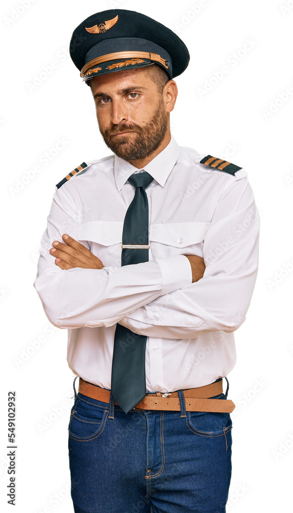 Handsome man with beard wearing airplane pilot uniform skeptic and nervous, disapproving expression on face with crossed arms. negative person. Handsome man with beard wearing airplane pilot uniform skeptic and nervous, disapproving expression on face with crossed arms. negative person.