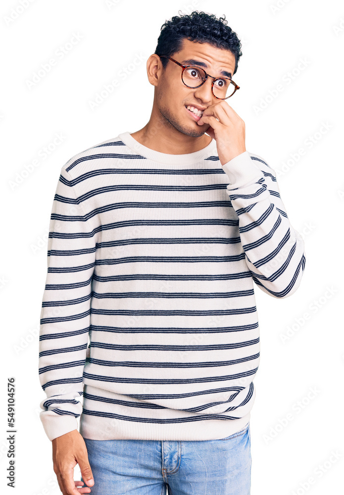 Hispanic handsome young man wearing casual clothes and glasses looking stressed and nervous with hands on mouth biting nails. anxiety problem. Hispanic handsome young man wearing casual clothes and glasses looking stressed and nervous with hands on mouth biting nails. anxiety problem.