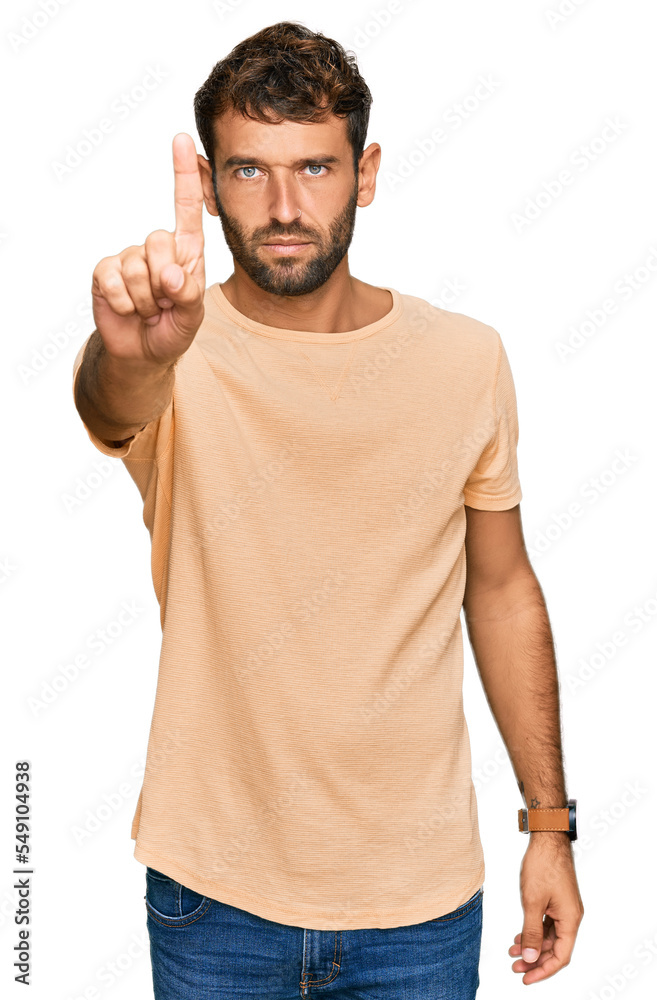 Handsome young man with beard wearing casual tshirt pointing with finger up and angry expression, showing no gesture Handsome young man with beard wearing casual tshirt pointing with finger up and angry expression, showing no gesture