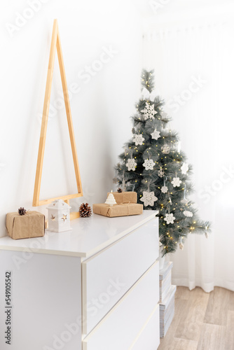 The chest of drawers is decorated with a wooden Christmas tree, gifts and candles. Eco style