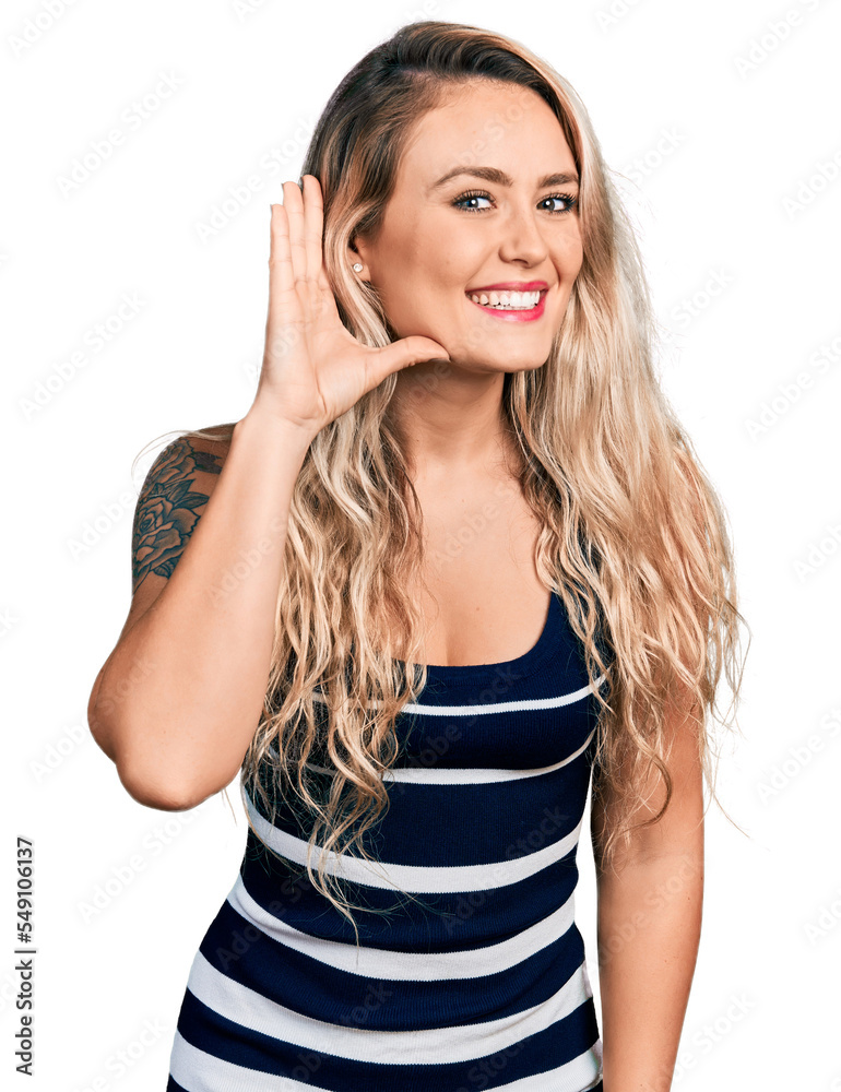 Young blonde woman wearing casual clothes smiling with hand over ear listening an hearing to rumor or gossip. deafness concept. Young blonde woman wearing casual clothes smiling with hand over ear listening an hearing to rumor or gossip. deafness concept.