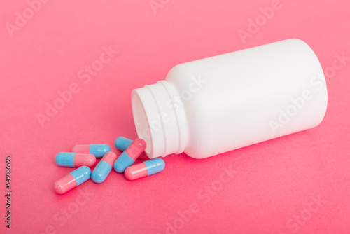 different drugs and health supplement pills poured from a medicine bottle health care and medical top view on colored background
