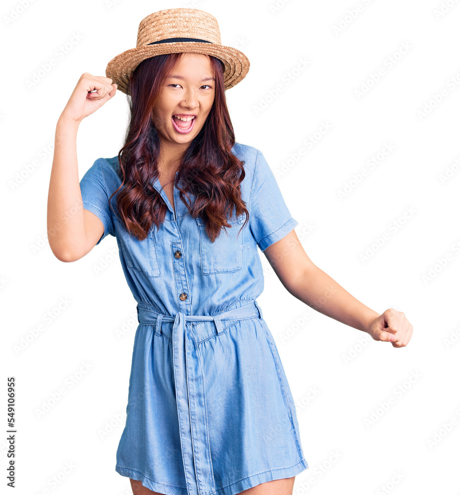 Young beautiful chinese girl wearing summer hat dancing happy and cheerful, smiling moving casual and confident listening to music Young beautiful chinese girl wearing summer hat dancing happy and cheerful, smiling moving casual and confident listening to music