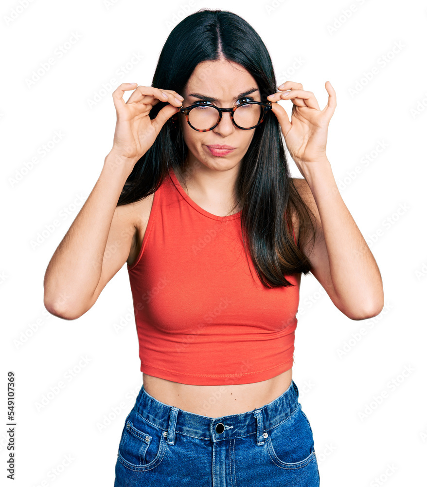 Young hispanic woman wearing casual clothes and holding glasses skeptic and nervous, frowning upset because of problem. negative person. Young hispanic woman wearing casual clothes and holding glasses skeptic and nervous, frowning upset because of problem. negative person.