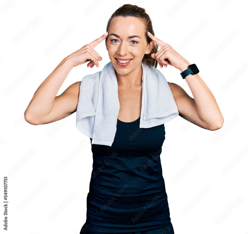 Young caucasian woman wearing sportswear and towel smiling pointing to head with both hands finger, great idea or thought, good memory Young caucasian woman wearing sportswear and towel smiling pointing to head with both hands finger, great idea or thought, good memory