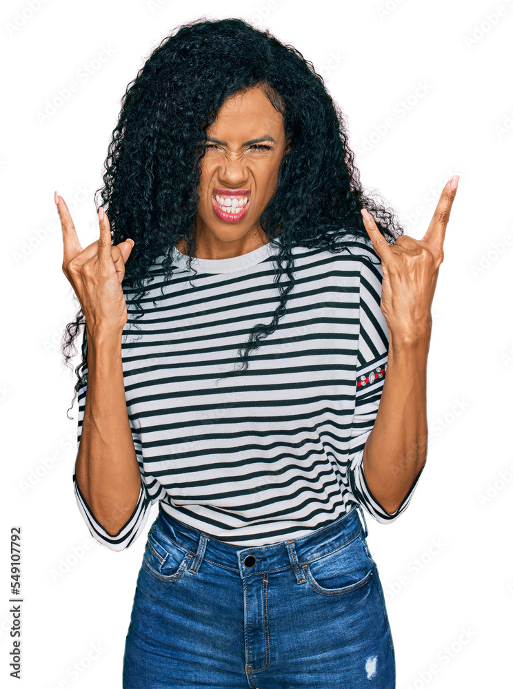 Middle age african american woman wearing casual clothes shouting with crazy expression doing rock symbol with hands up. music star. heavy concept. Middle age african american woman wearing casual clothes shouting with crazy expression doing rock symbol with hands up. music star. heavy concept.