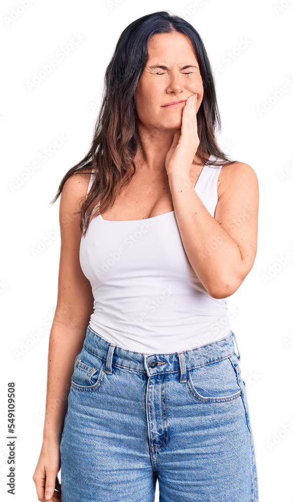 Young beautiful brunette woman wearing casual sleeveless t-shirt touching mouth with hand with painful expression because of toothache or dental illness on teeth. dentist Young beautiful brunette woman wearing casual sleeveless t-shirt touching mouth with hand with painful expression because of toothache or dental illness on teeth. dentist