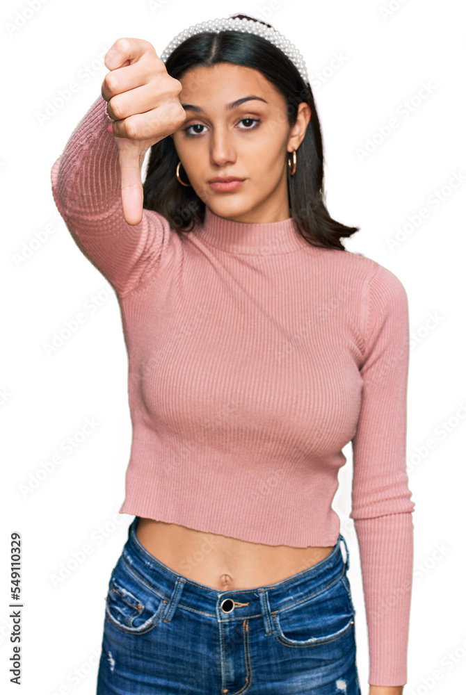 Young hispanic girl wearing casual clothes looking unhappy and angry showing rejection and negative with thumbs down gesture. bad expression. Young hispanic girl wearing casual clothes looking unhappy and angry showing rejection and negative with thumbs down gesture. bad expression.